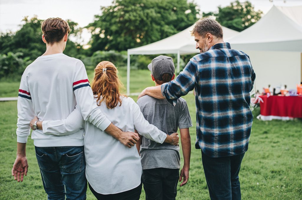 Family walking together at an outdoor gathering, supporting each other
